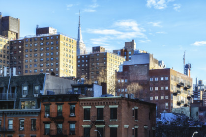 A street view of apartment buildings with the Empire State Building in the background at the High Line