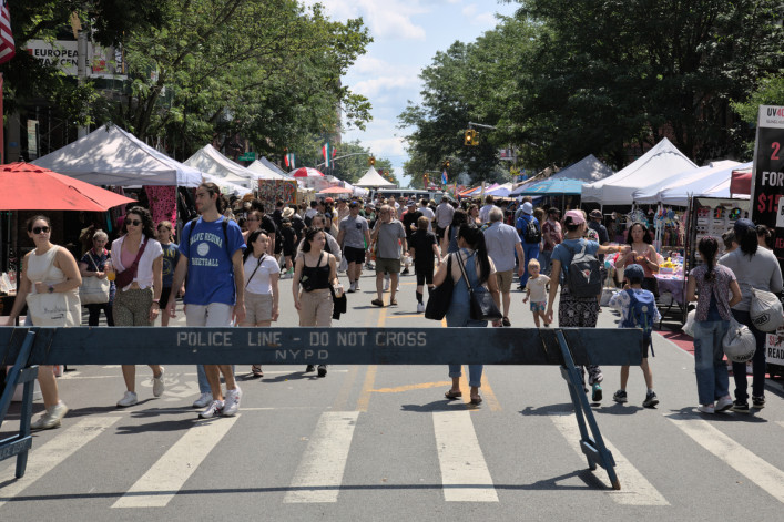 Participants walk down closed street during 7th Heaven fair in Park Slope with vendor stalls