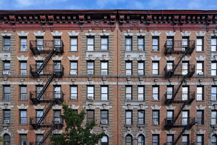 Old fashioned New York City apartment building with decorative roof cornice and external fire escapes