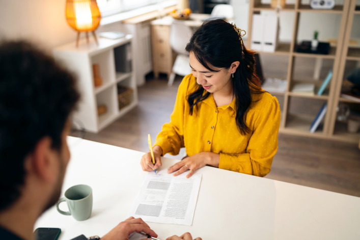 Young woman, signing a contract during an meeting with a male real estate agent