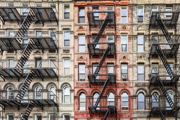 Exterior view of old New York City style architecture apartment building with windows and fire escapes