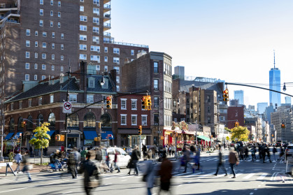 Busy crowds of people walking across the street at 7th Avenue in the Greenwich Village neighborhood of New York City NYC