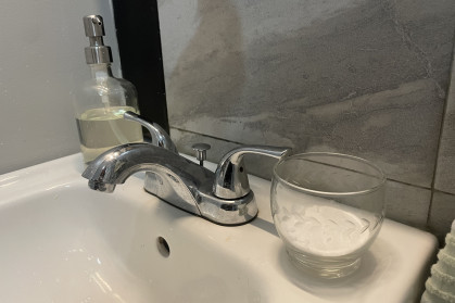 A cup of baking soda sits on a bathroom sink.