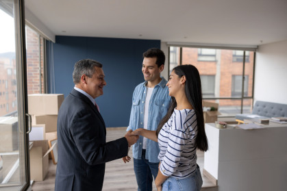 Real Estate Agent selling an apartment to a couple and closing the deal with a handshake stock photo