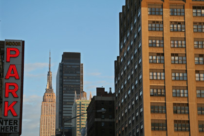 A photo of NYC buildings and a parking garage sign on the left