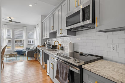 A kitchen with stainless steel appliances and counter tops and wood floor