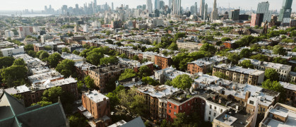 A view of short Brooklyn buildings with the Manhattan skyline in the background