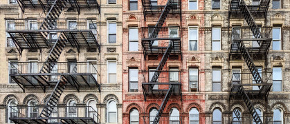 Exterior view of old New York City style architecture apartment building with windows and fire escapes