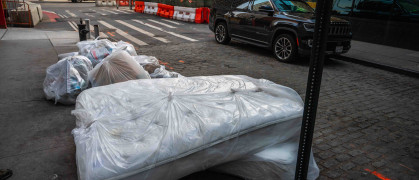 New York, NY, USA 07-18-2023 Mattresses wrapped in plastic on sidewalk out for trash with garbage bags on a Manhattan street. Editorial use only.