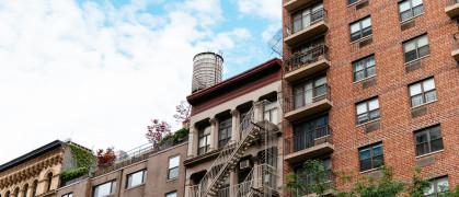 Cityscape of Manhattan with old buildings and water tower against sky