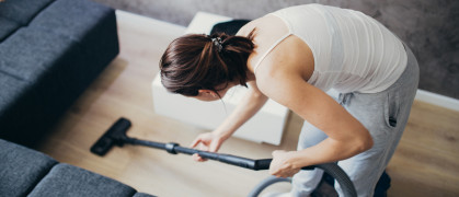 woman vacuuming the floor next to her couch